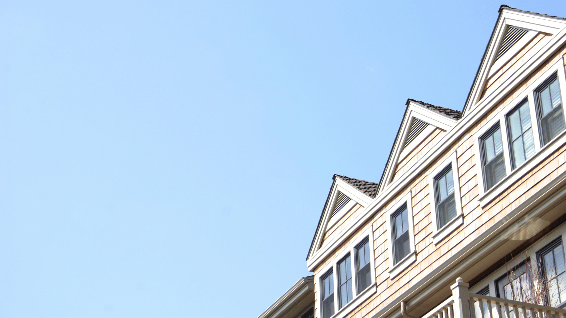 Cedar-shingle home with dormer windows against a clear blue sky
